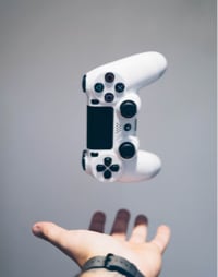 A white Playstation controller hovers above an outstretched hand.