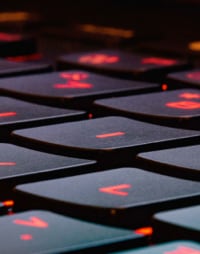 Close-up of a laptop keyboard, the keys emitting a red LED glow.